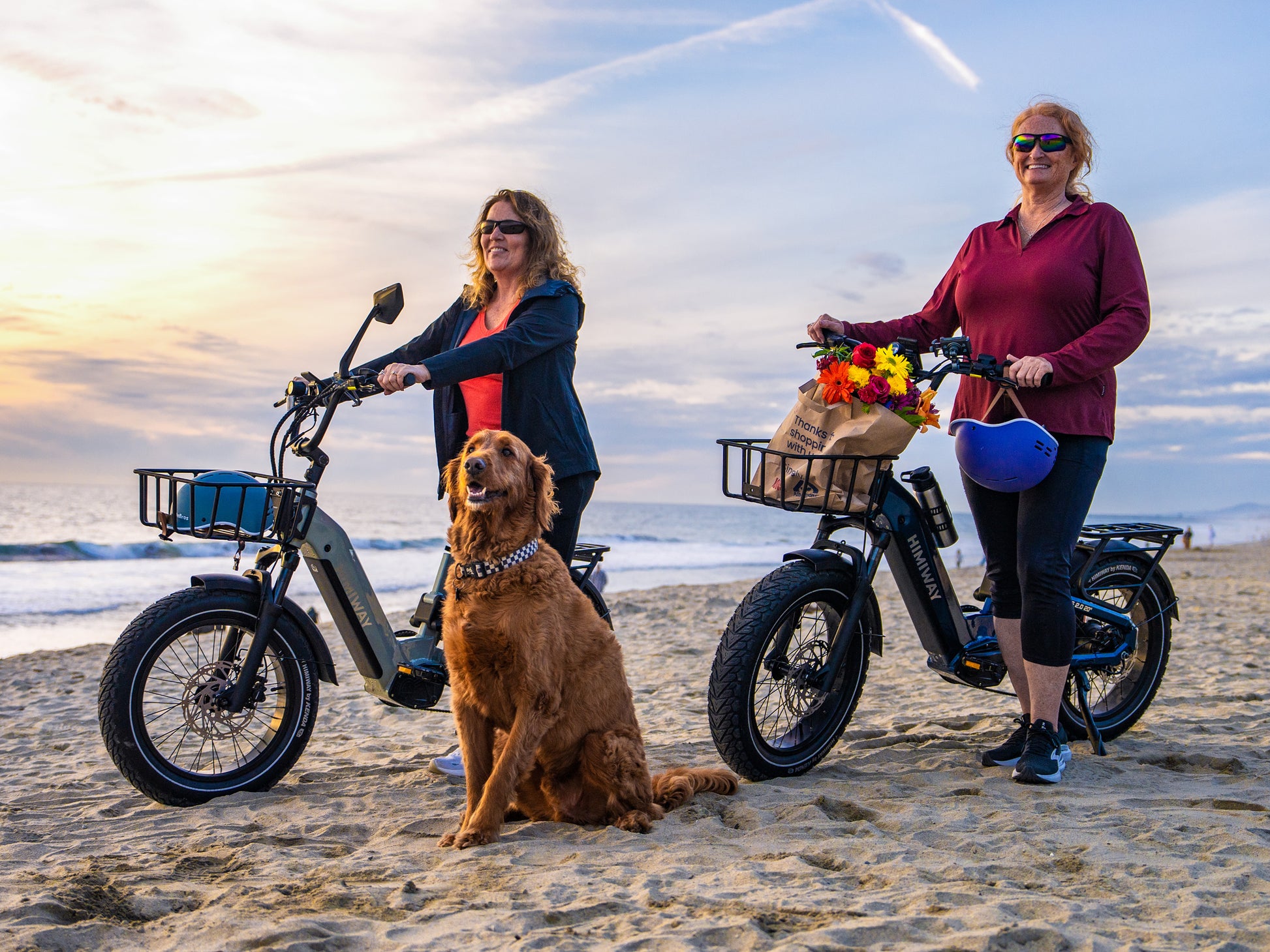 Two senior women and their dog standing on a sandy beach with Himiway D5 2.0 20" full suspension step-thru fat tire electric bikes.