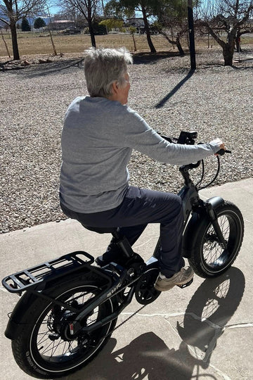 Himiway D5 2.0 20-inch electric bike with a white-haired senior woman riding on an asphalt road beside a gravel path
