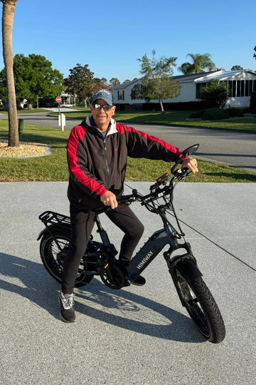 An older adult enjoying a sunny day with his Himiway D5 2.0 e-bike on a paved driveway.